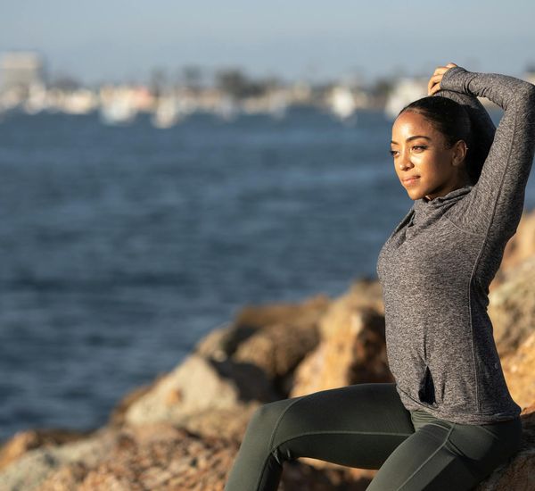 Person stretching gently outdoors during a sunny morning.